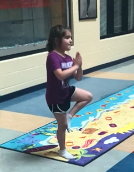 child on sensory island path doing a palm tree yoga position